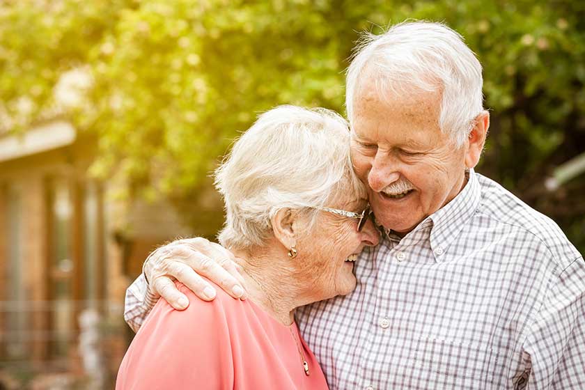 older couple are standing in the garden, hugging each other and laughing at each other older couple are standing in the garden, hugging each other and laughing at each other