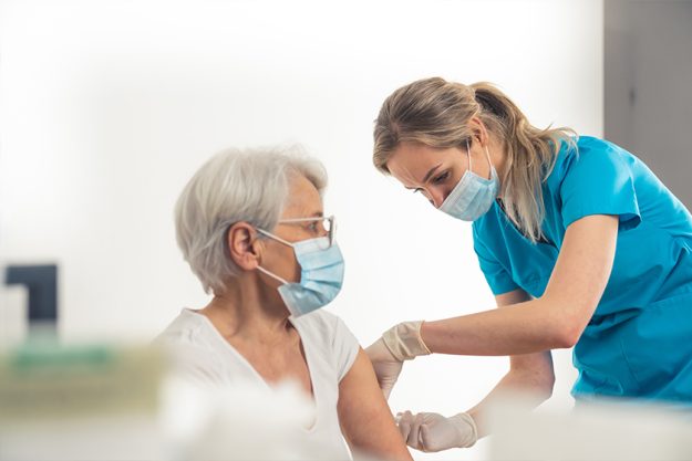 Young nurse working in a medical clinic helps out with vaccination process