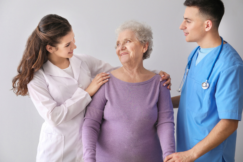 Young medical workers with senior woman on grey background The Basic Terminology In Senior Living Communities Explained