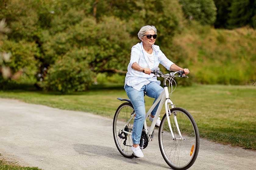 Happy senior woman riding bicycle at summer park