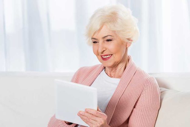 Portrait of cheerful senior woman using digital tablet