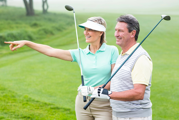 golfing-couple-smiling-and-holding-clubs golfing-couple-smiling-and-holding-clubs