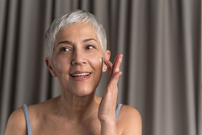 Gorgeous nourished mature woman with short hair applying face cream with her finger Gorgeous nourished mature woman with short hair applying face cream with her finger