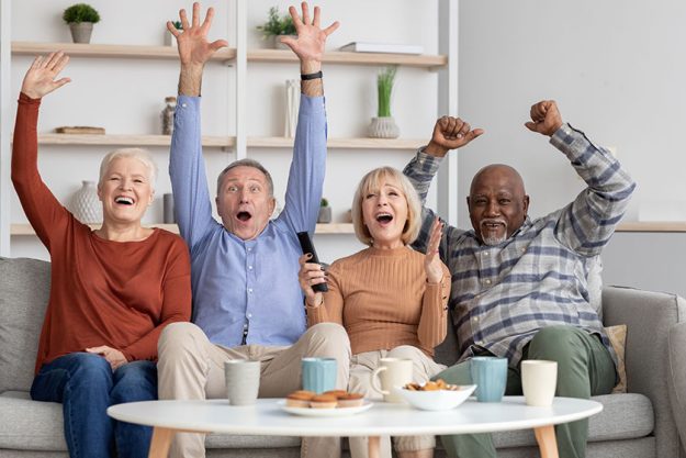Happy multiracial elderly people watching football game on TV Happy multiracial elderly people watching football game on TV