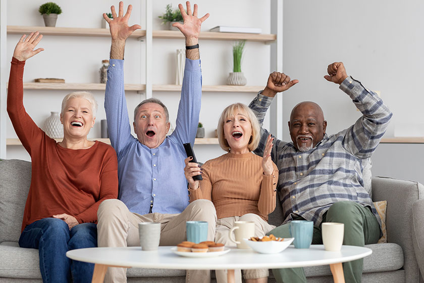 Happy multiracial elderly people watching football game on TV Happy multiracial elderly people watching football game on TV