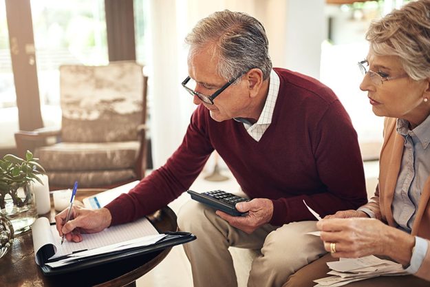 Keeping note of all our spendings. Shot of an elderly couple working out a budget while sitting on the living room sofa.
