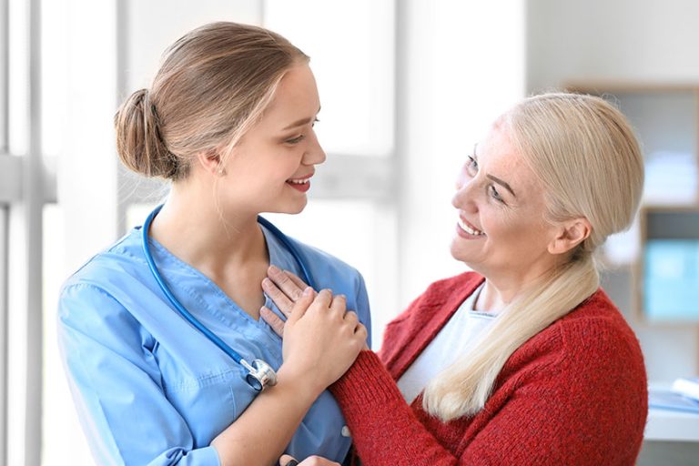 Medical assistant with mature patient in clinic