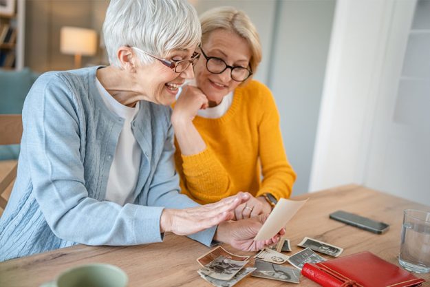 Senior mature women friends or sisters looking family photo album