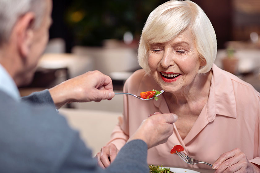 Charming mature woman eating from mans fork
