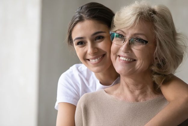 Smiling mature mother and adult daughter look in distance dreaming Smiling mature mother and adult daughter look in distance dreaming