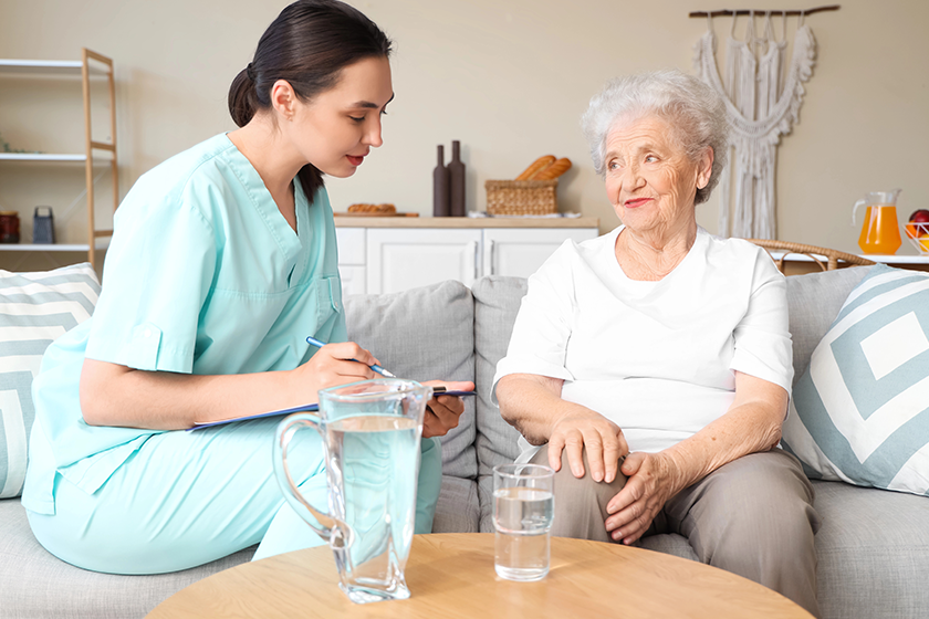 Physical therapist writing in clipboard with senior woman