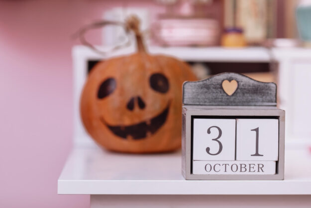 Wooden calendar show date 31 october halloween day and pumpkin on wooden school table in the girls pink room. Halloween decorations concept