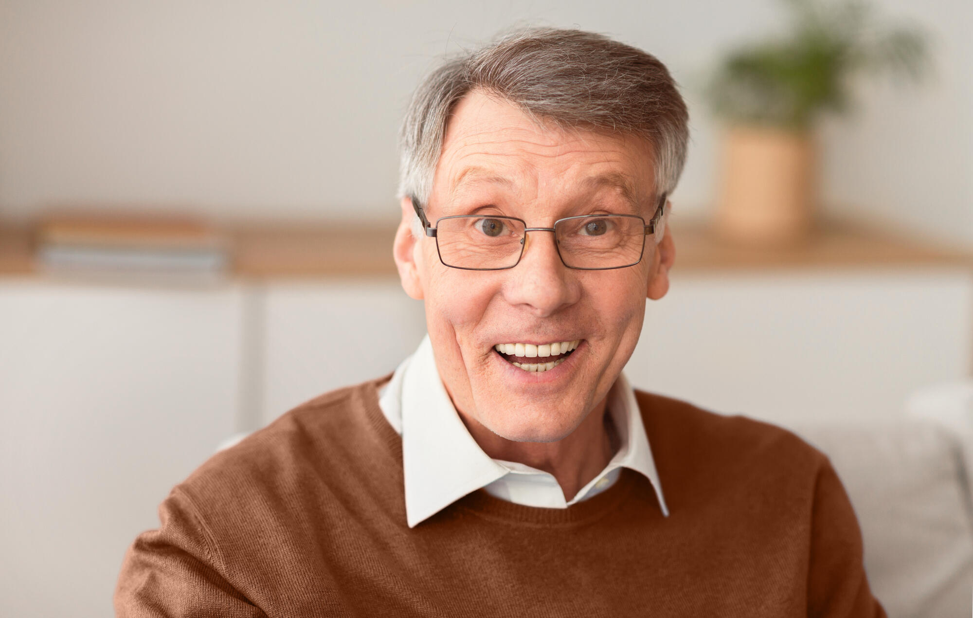 Excited Senior Man Smiling Sitting On Sofa At Home