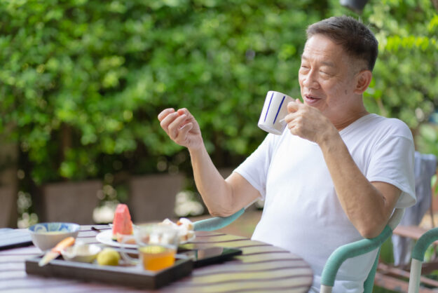 senior asian man eating healthy breakfast in garden